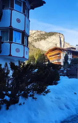 a snow covered building with snow covered cars in front at Garni Hotel Rezia in Selva di Val Gardena