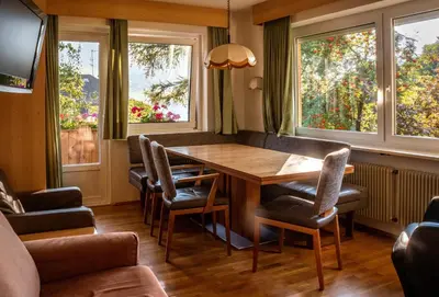 a dining room with a table and chairs and windows at AppartChalet LA RONDULA - 100m from Seceda in Ortisei
