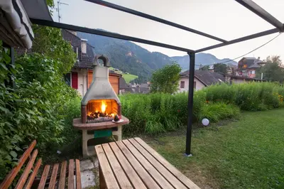 a outdoor fireplace in a yard with a bench at AppartChalet LA RONDULA - 100m from Seceda in Ortisei