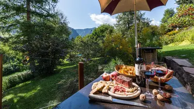 a table with a plate of food and a bottle of wine at AppartChalet LA RONDULA - 100m from Seceda in Ortisei