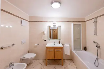 a bathroom with a sink and a toilet and a tub at Residence Bosco Verde in San Cassiano