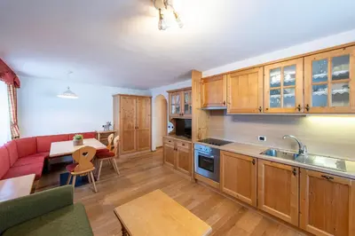 a kitchen with wooden cabinets and a red couch at Residence Bosco Verde in San Cassiano