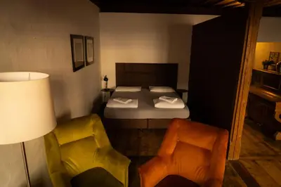 a bedroom with a bed and two chairs at Residence Fink Central Apartments in Bolzano