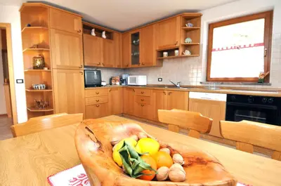 a kitchen with a wooden bowl of fruit on a table at CHALET VILLA RITA in Tesero