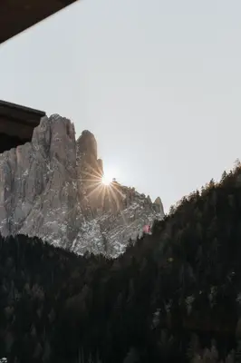 a mountain with the sun shining on it at B&B Hotel Mirabel in Ortisei
