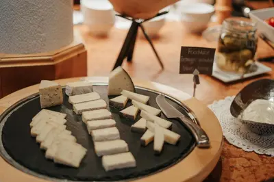 a plate of food with cheese on a table at B&B Hotel Mirabel in Ortisei