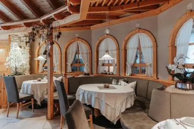 a restaurant with two tables and chairs and windows at B&B Hotel Mirabel in Ortisei