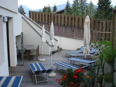two umbrellas and lounge chairs on a patio at Sporthotel Rasen in Rasùn di Sotto