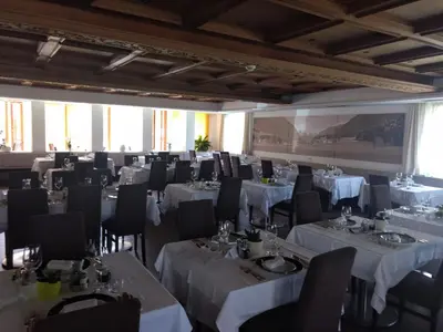 a dining room with tables and chairs and windows at Sporthotel Rasen in Rasùn di Sotto