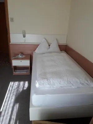 a bedroom with a bed and a nightstand with a white bed sidx sidx sidx at Hotel Lux in Merano