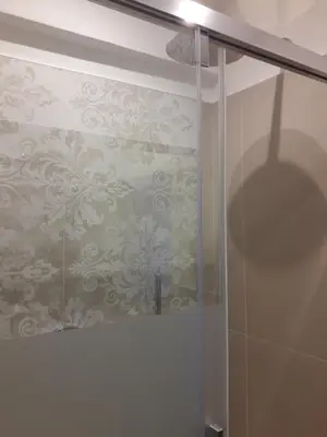 a bathroom with a shower stall with a wallpaper at Hotel Lux in Merano