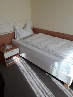 a bed in a room with a side table at Hotel Lux in Merano