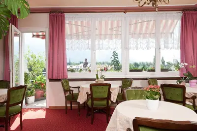 a dining room with tables and chairs and windows at Hotel Lux in Merano