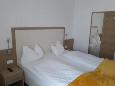 a bedroom with two white beds and a mirror at Hotel Lux in Merano