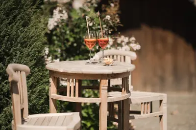 two glasses of wine sitting on a table with two chairs at Untermairhof in Lagundo