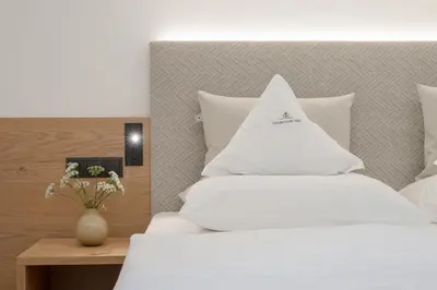 a bedroom with two white beds and a vase with flowers at Untermairhof in Lagundo