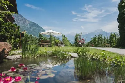 a garden with a pond with flowers and an umbrella at Untermairhof in Lagundo