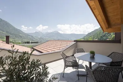 a balcony with a table and chairs and mountains at Untermairhof in Lagundo