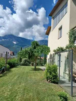 a house with a grass yard next to a building at Das Landhaus in Terlano