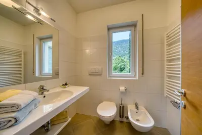 a bathroom with a sink and a toilet and a window at Das Landhaus in Terlano