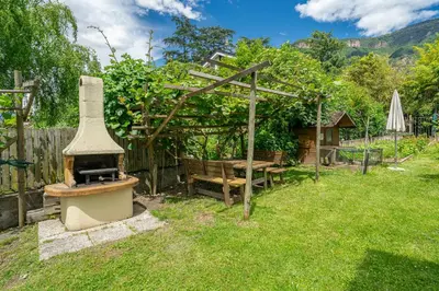 a backyard with an outdoor oven in the grass at Das Landhaus in Terlano