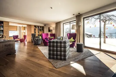 a living room with purple chairs and a large window at Hotel Dolomitenblick in Terento