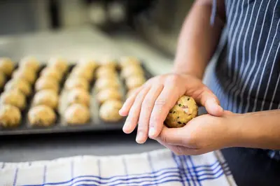 a person holding a potato in their hands with a tray of doughnuts at Hotel Dolomitenblick in Terento