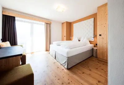 a hotel room with two beds and a large window at Hotel Dolomitenblick in Terento