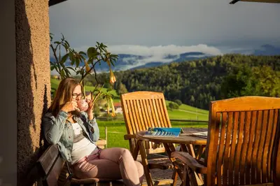 a woman sitting on a porch talking on a cell phone at Hotel Dolomitenblick in Terento
