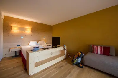 a bedroom with a bed and a couch and a desk at Hotel Dolomitenblick in Terento