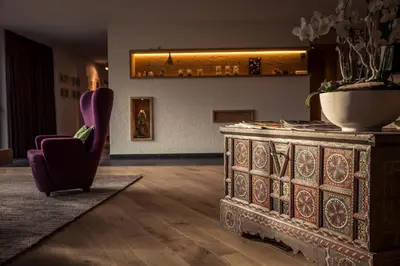 a living room with a purple chair and a table at Hotel Dolomitenblick in Terento
