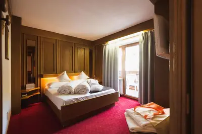 a bedroom with a bed and a desk and a mirror at Hotel Catinaccio in Vigo di Fassa