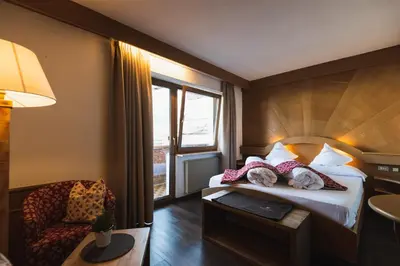 a bedroom with a bed with white pillows at Hotel Catinaccio in Vigo di Fassa