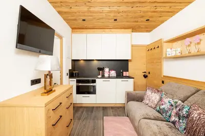 a living room with a couch and a kitchen at Chalets 4 Sorus & Apartments La Villetta in Colfosco