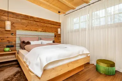 a bedroom with a bed and a wooden wall at Chalets 4 Sorus & Apartments La Villetta in Colfosco