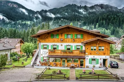 a large wooden house with green shuttered windows at Majon del Tisler in Canazei