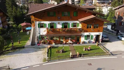 a building with people sitting on the grass in front of it at Majon del Tisler in Canazei