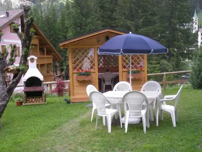 a table and chairs with an umbrella and a gazebo at Majon del Tisler in Canazei