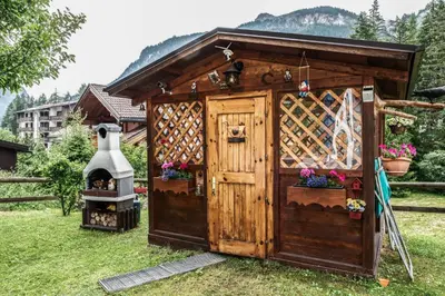a small wooden out house with a grill at Majon del Tisler in Canazei