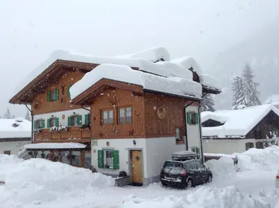 a snow covered house with a car parked in front of it at Majon del Tisler in Canazei