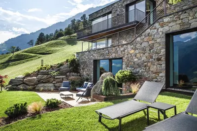 a stone house on a hill with chairs in the yard at Chalet in Naturno