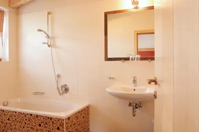 a bathroom with a sink and a tub and a mirror at Garnì Iosc in San Vigilio Di Marebbe