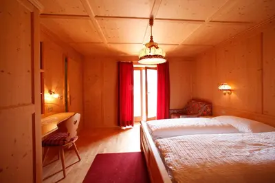 a bedroom with two beds and a desk and a window at Garnì Iosc in San Vigilio Di Marebbe