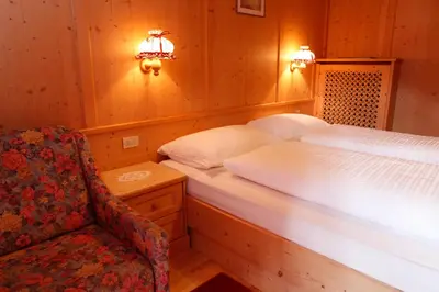 a bedroom with a bed and a chair and lights at Garnì Iosc in San Vigilio Di Marebbe