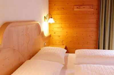two beds in a room with a wooden wall at Garnì Iosc in San Vigilio Di Marebbe