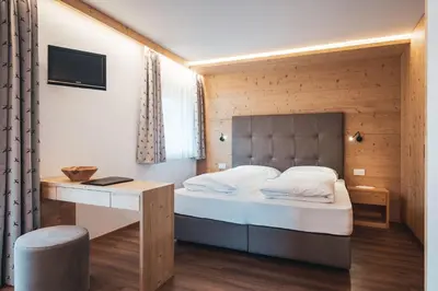 a bedroom with a bed and a desk in a room at Garnì Iosc in San Vigilio Di Marebbe