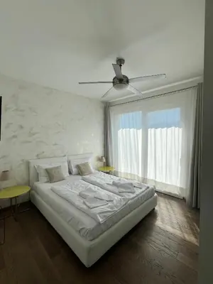 a white bedroom with a bed and a ceiling fan at B&B Mele d'Oro in Bolzano