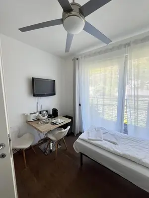 a bedroom with a bed and a desk and a ceiling fan at B&B Mele d'Oro in Bolzano