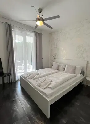 a large white bed in a room with a ceiling fan at B&B Mele d'Oro in Bolzano