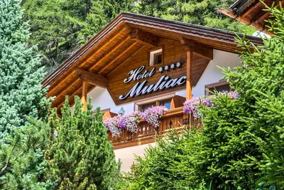 a building with a balcony with flowers on it at Hotel Muliac in Selva di Val Gardena